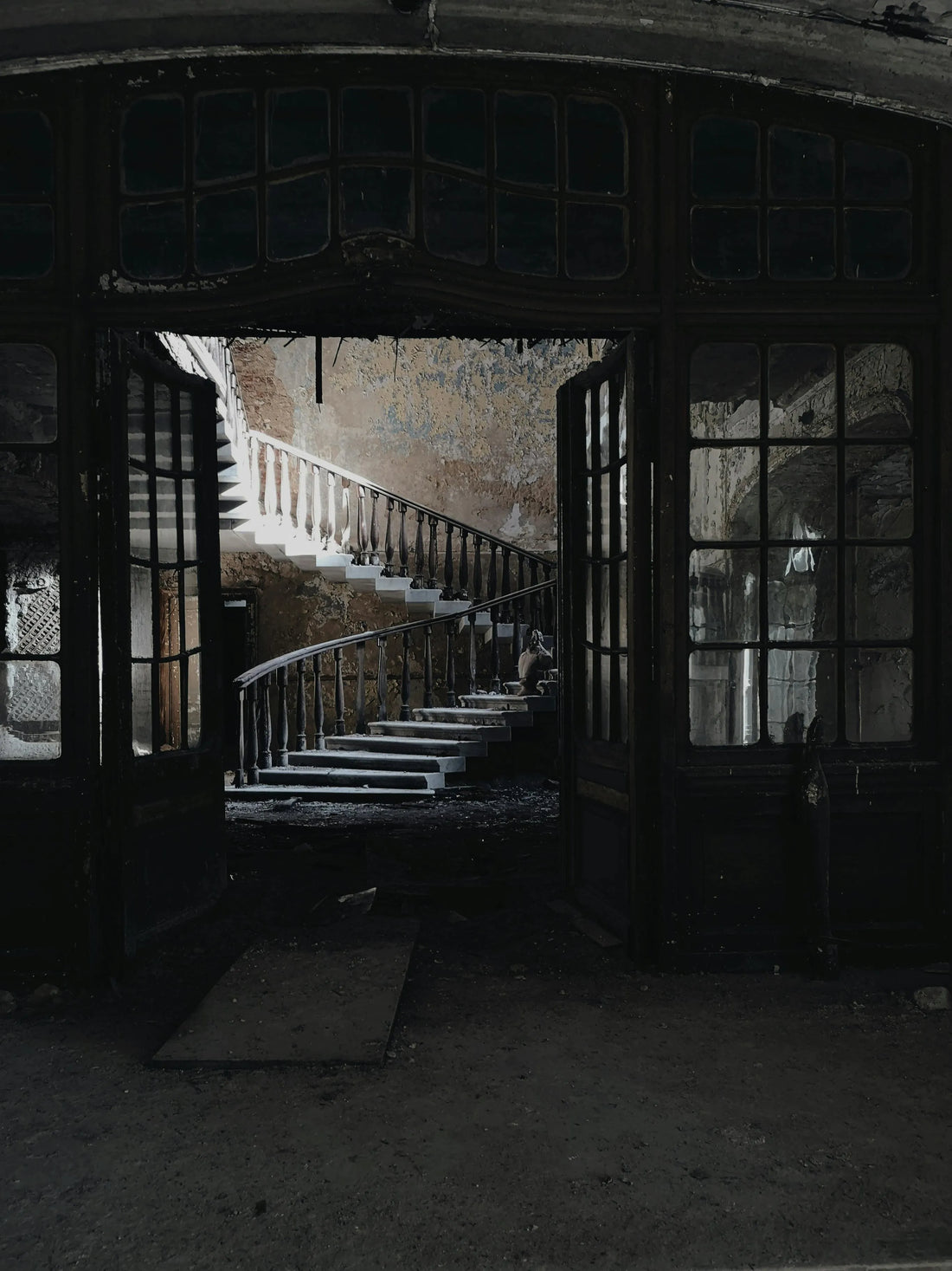 A dark old room in shambles leading to a staircase